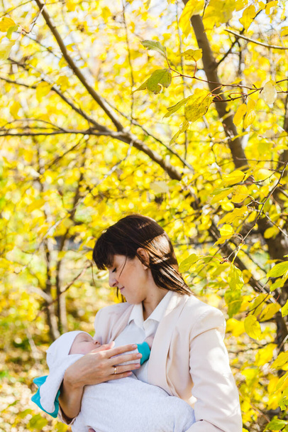 Mãe com um bebê, um menino pequeno caminha no outono no parque ou na floresta. Folhas amarelas, a beleza da natureza. Comunicação entre um filho e um pai. - Foto, Imagem