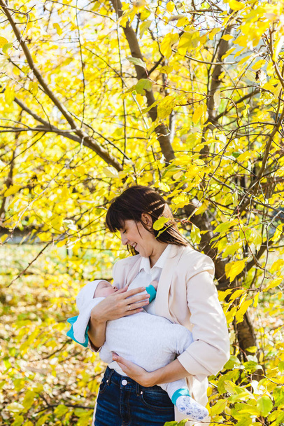 Mom with a baby, a small boy walks in the fall in the Park or forest. Yellow leaves, the beauty of nature. Communication between a child and a parent. - Photo, Image