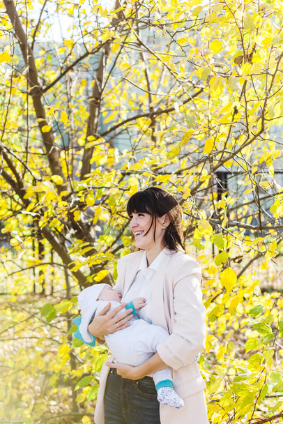 Mom with a baby, a small boy walks in the fall in the Park or forest. Yellow leaves, the beauty of nature. Communication between a child and a parent. - 写真・画像