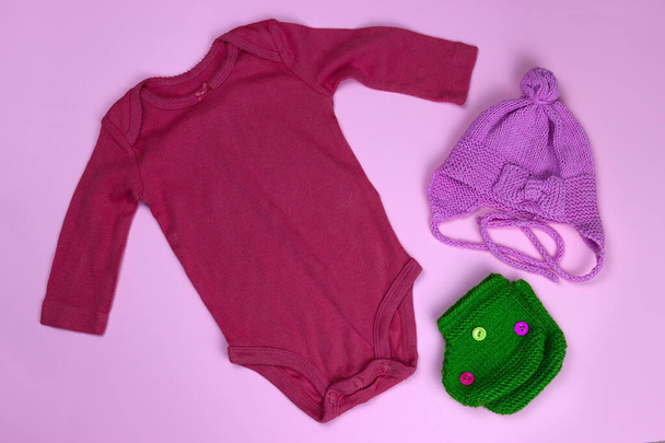 新生児の服の体と靴下とピンクの背景の帽子 - 写真・画像