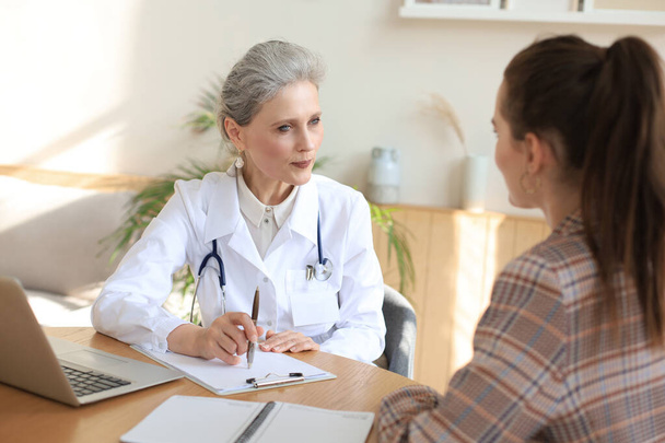 Middle aged female doctor therapist in consultation with patient in office - Photo, Image