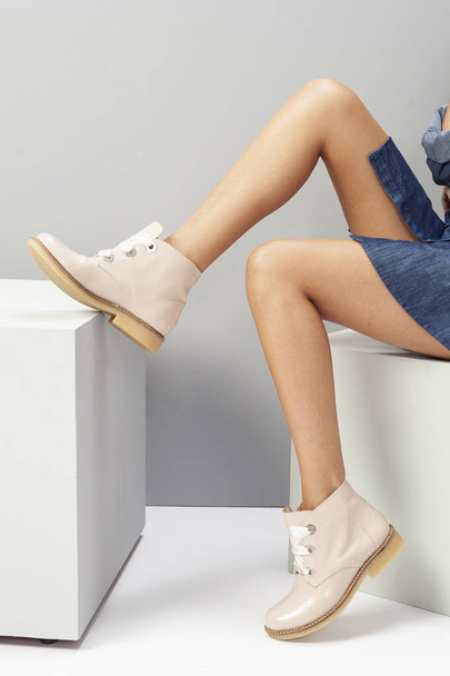 a sitting female model with  cream shoes and the right foot on the box - Фото, изображение