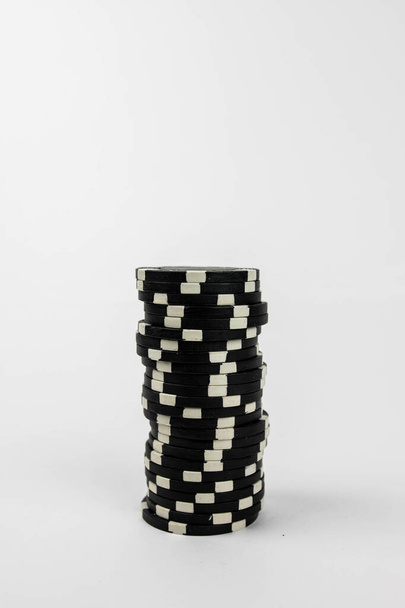 a vertical shot of  black poker chips over white background - Фото, изображение