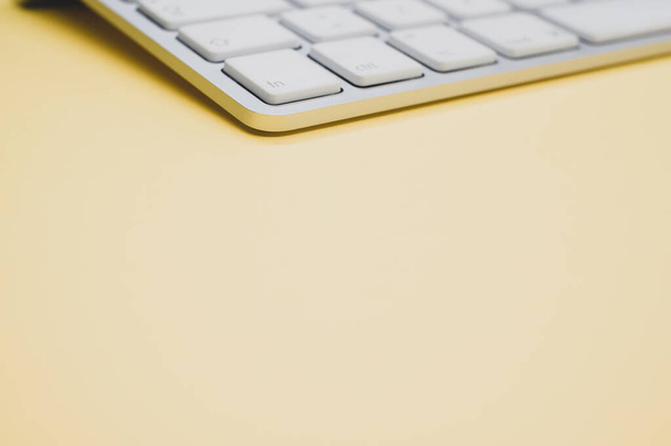 A closeup of a modern and clean keyboard on a yellow surface - Fotoğraf, Görsel