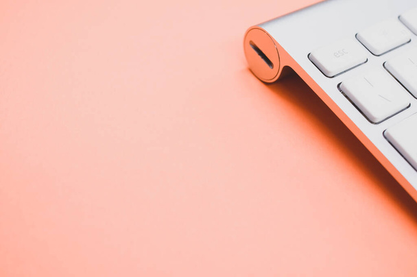 A closeup of a modern and clean keyboard on an orange surface - Foto, Bild