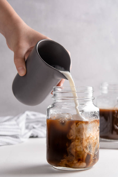 a vertical shot of making a coffee milk latte in a jar - Фото, изображение