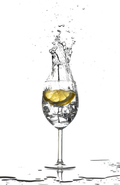 A vertical shot of a glass of water with lemon and ice on white background - Fotografie, Obrázek