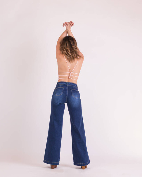 A vertical shot of a female wearing wide-legged jeans in a studio - 写真・画像