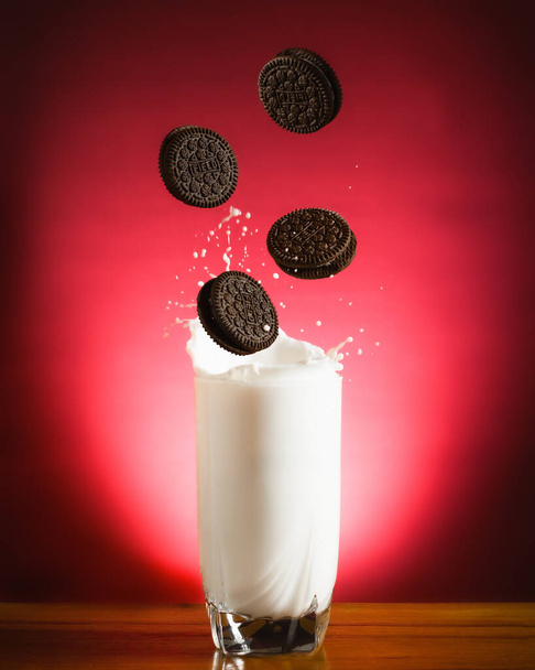 A vertical shot of biscuits falling into the glass of milk - Photo, Image