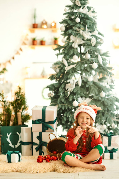Portrait of happy child in pajama in the kitchen on the Christmas tree background - Фото, изображение