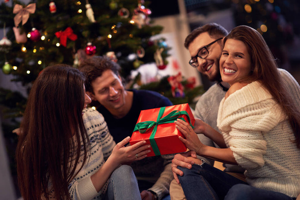 Freundeskreis mit Geschenken feiert Weihnachten zu Hause - Foto, Bild