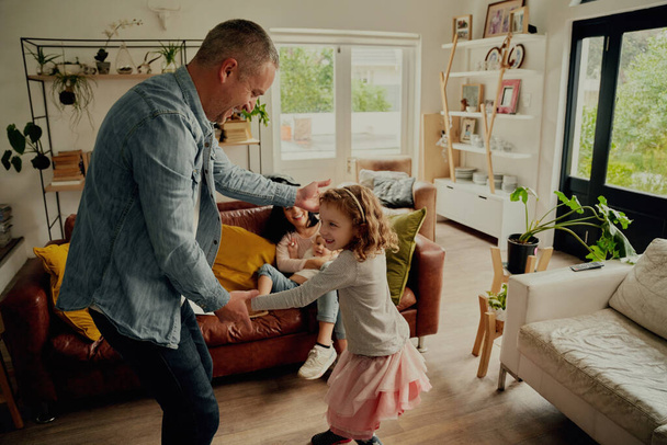 Cheerful father and daughter playing and dancing at home holding hands - Photo, image