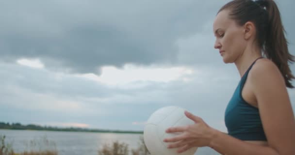 dienen in beachvolleybal, jonge vrouwelijke speler houdt bal in handen, overgeven en opvallend, medium portret - Video