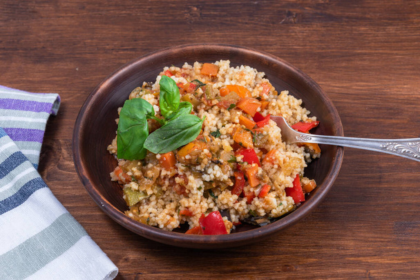 Couscous with stewed vegetables is a Moroccan, Algerian and Tunisian dish. Couscous mixed with stewed vegetables in a traditional clay plate - Photo, Image