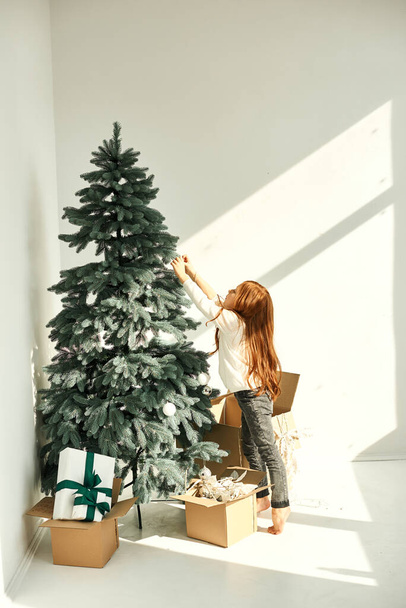 A little girl decorated Christmas tree on a white - Foto, Imagen