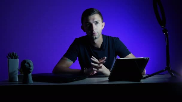 Blogger grabando opinión en video para redes sociales con luz led azul sobre fondo. - Imágenes, Vídeo