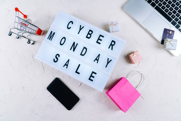 Top view of laptop, cyber monday promotion sale words on lightbox, gift boxes, laptop , shopping cart and bag, credit bank card on table. Online shopping, Sale, e-shopping, ordering, payment.concept. - Фото, изображение
