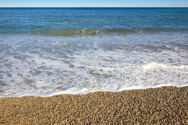 バレンシアの地中海の小石のビーチと青い海。スペイン - 写真・画像