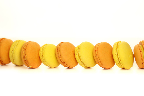 Isolated macaroon on a white background. Popular dessert. Photo for formula. Macaroons in the studio. yellow and orange macaroons in a row on a white background - Fotografie, Obrázek