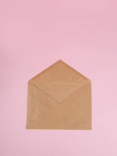 Brown craft envelope on a pink background. - Zdjęcie, obraz