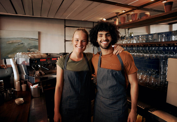 Young cafe owners wearing apron standing behind counter in cafe looking at camera - Foto, Imagen