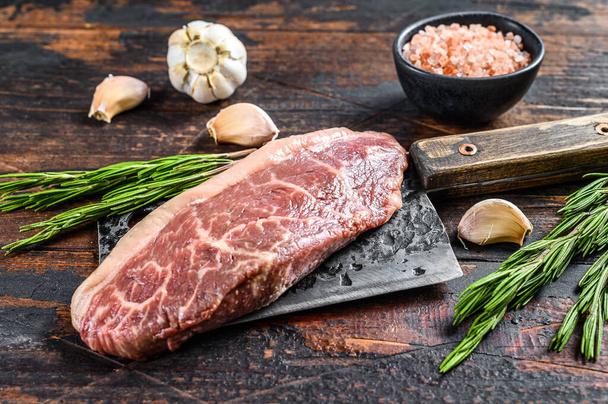 Raw rump cap steak on a meat cleaver. Dark wooden background. Top view. - Photo, Image