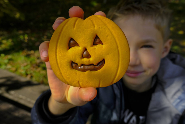 mignon enfant tenant dans les mains Halloween biscuit à la citrouille avec chocolat gros plan. Vacances d'Halloween. Aliments sucrés.  - Photo, image