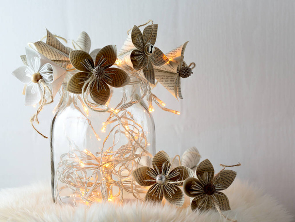Flores de origami hechas de hojas de libros con luces led en una maceta de vidrio - Foto, imagen