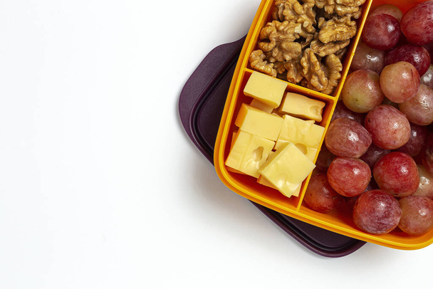 Healthy Food in Plastic containers ready to eat with Cheese, grapes and walnuts on the work table. To take away.walnuts. Isolated - Photo, image