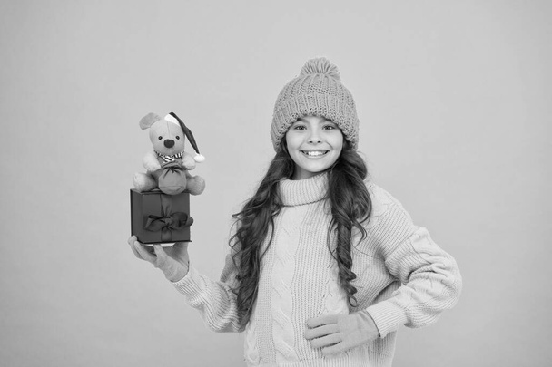 Shop for kids. Happy 2020 year. Gift for good luck. Successful rat year. Appease with gift. Shopping tips. Happy girl hold mouse toy and wrapped gift box. Kid knitted sweater and hat play plush toy - Fotografie, Obrázek