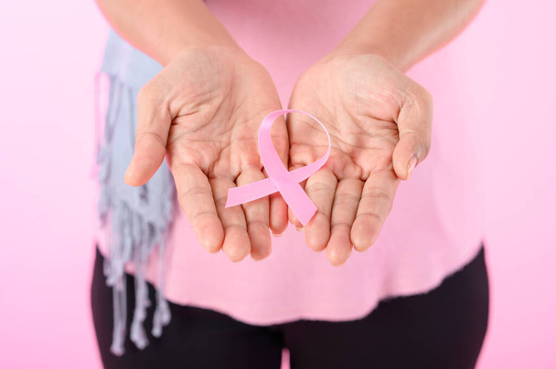 Femme musulmane portant un hijab avec un ruban sur la poitrine montre la prévention du cancer du sein. Sur fond rose, concept de cancer du sein, concept de prévention du cancer. - Photo, image
