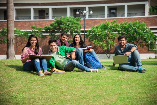 Kolej öğrencilerinden oluşan neşeli Hintli genç bir grup ya da arkadaşlar kampüste otururken, ayakta ya da yürürken birlikte gülüyorlar. - Fotoğraf, Görsel
