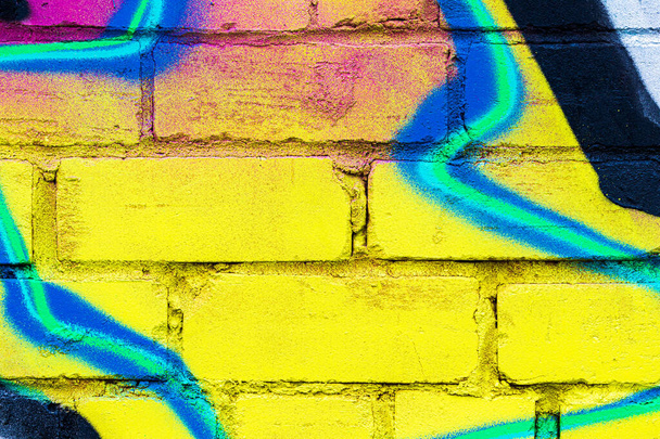 Ένα κομμάτι από πολύχρωμα γκράφιτι ζωγραφισμένο σε έναν τοίχο από τούβλα. Αφηρημένο φόντο για σχεδιασμό. - Φωτογραφία, εικόνα