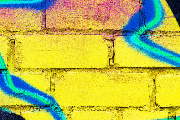 Ένα κομμάτι από πολύχρωμα γκράφιτι ζωγραφισμένο σε έναν τοίχο από τούβλα. Αφηρημένο φόντο για σχεδιασμό. - Φωτογραφία, εικόνα