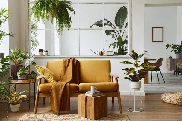 Interior design of scandinavian open space with yellow velvet sofa, plants, furniture, book, wooden cube and personal accessories in stylish home staging. Template. - Fotó, kép