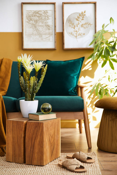 Stylish scandinavian interior of living room with design green velvet sofa, gold pouf, wooden furniture, plants, carpet, cube and mock up poster frames. Template. - Foto, Bild