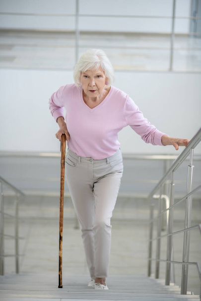 Elderly woman with a walking stick going upstairs - Zdjęcie, obraz