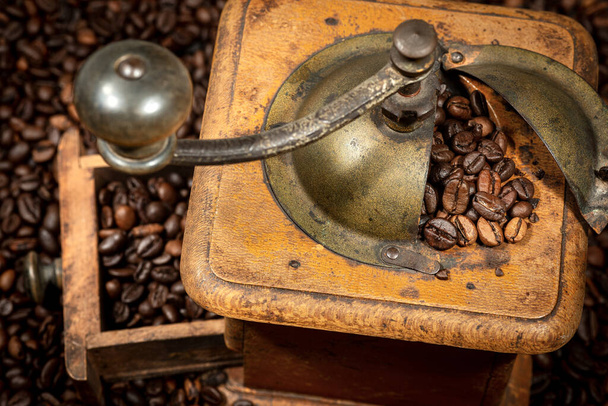 Detailní záběr staré ruční mlýnky na kávu z kovu a dřeva s praženými kávovými zrny, Veneto, Itálie, Evropa. - Fotografie, Obrázek