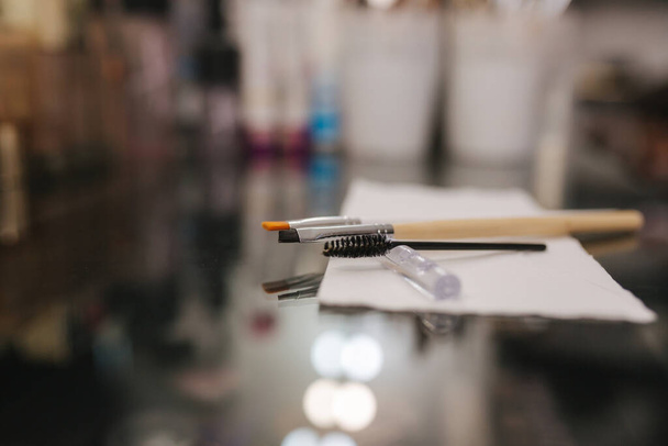 Close-up do local de trabalho do mestre de sobrancelha. Mesa com escovas e henna para sobrancelhas - Foto, Imagem