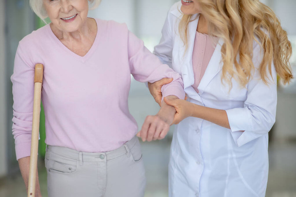 Nurse supporting an elderly woman in a pink shirt - Fotoğraf, Görsel