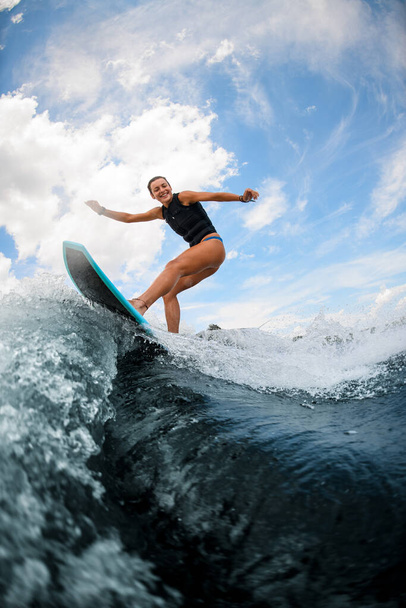 Sporty woman having fun and jumping on the board on the river - Фото, зображення