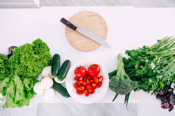 Delicious assortment of farm fresh vegetables with knife on wooden board, top view. - Photo, Image