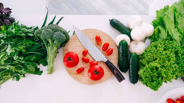 Surtido de verduras ecológicas en mesa de cocina con tabla de cortar y cuchillo, receta vegetariana, vista superior - Foto, imagen