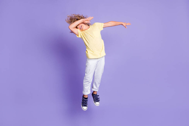 Küçük dabber çocuğun tam vücut fotoğrafı kollarını kapat beyaz sarı tişört pantolon giy mor arkaplan üzerine izole edilmiş - Fotoğraf, Görsel