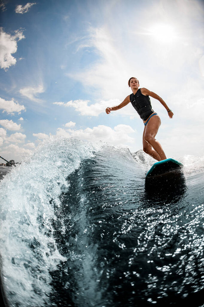 view of woman who rides on the wake surf on high wave against blue sky - Foto, Imagen