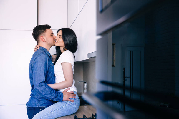 Side profil fénykép gyengéd gondoskodó házaspár tartózkodó otthon ölelés együtt nő ül a konyhaasztalnál. - Fotó, kép