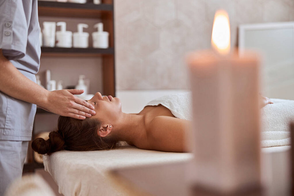 Jonge aantrekkelijke vrouw in massage salon is het hebben van schoonheid en gezondheidszorg procedures - Foto, afbeelding
