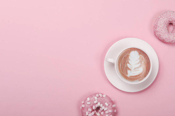 Composición plana con rosquillas y taza de café sobre fondo rosa - Foto, imagen