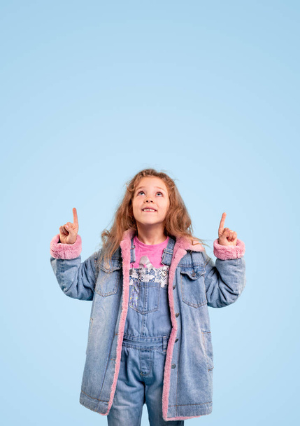 Stylish girl in denim outfit pointing up - Foto, Bild