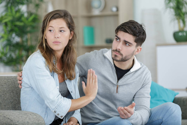 resentful girl sitting next to boyfriend on couch at home - Photo, Image
